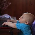 Cute baby boy engaged with a laptop indoors, showing early tech curiosity.